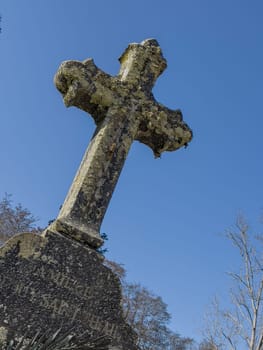 A tranquil afternoon reveals La Croix du Cimetiere at Eglise Saint Pierre, surrounded by ancient graves and lush greenery in Mons, Gironde, France, reflecting a sense of peace.