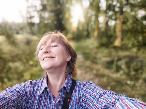 A mature woman takes a selfie amid a lush natural landscape during her adventure in the great outdoors.