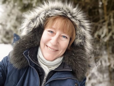 A woman captures a cheerful selfie in a snowy setting, showcasing her joy as a tourist enjoying the winter landscape during her adventure.
