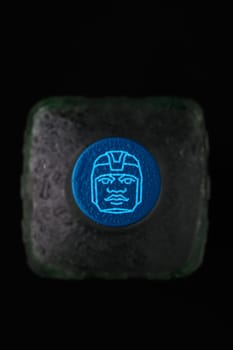 Gaziveren Cyprus -12.03.2025 Tequila Olmeca A glowing blue ice cube with a unique face design contrasts beautifully with the dark background.