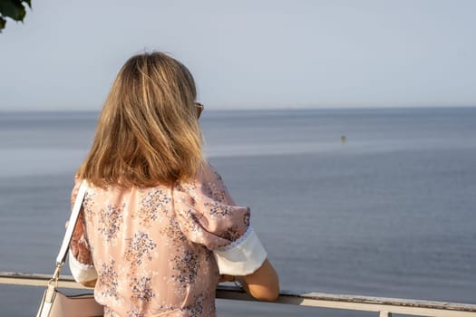A visitor gazes out over the calm waters of the Baltic Sea from a scenic viewpoint in Peterhof, appreciating the tranquil atmosphere and nature.