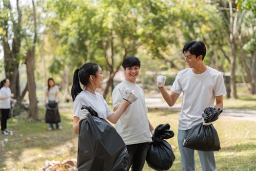 Three young volunteers share a joyful moment after collecting trash, promoting sustainability and teamwork.