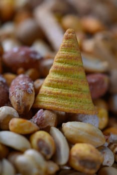 Vibrant cone-shaped treat stands out amidst an array of mixed nuts and seeds, showcasing a delightful snack experience.
