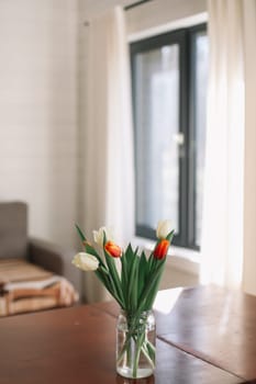 Beautiful bouquet of tulips in glass vase on table. Space for text. High quality photo