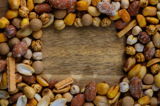 Vibrant collection of various nuts and snacks creates an inviting border on a rustic wooden tabletop.