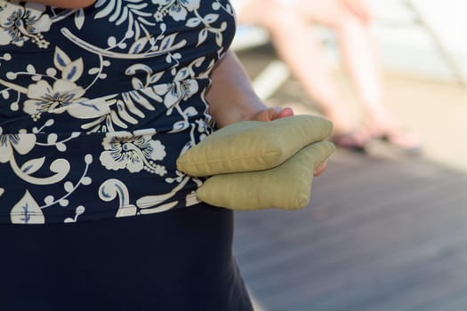Vivid portrayal of a person gripping cornhole bags firmly, combining dynamic action with soft focus on their summery floral attire.