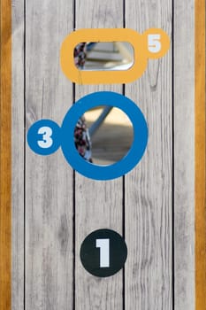 Close-up of a wooden cornhole game board with numbered scoring zones in bright colors, designed for fun and competitive outdoor activities.
