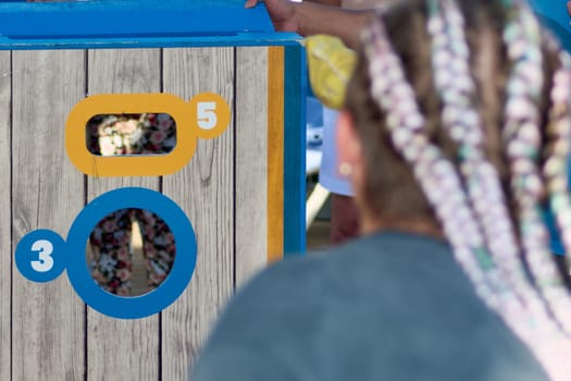 Action shot of a female cornhole player aiming at a colorful game board, capturing the competitive spirit and outdoor energy.