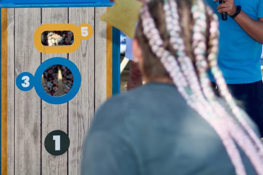 A close-up of a cornhole game scene highlighting a determined female player ready to score on a bright board in a fun competition.