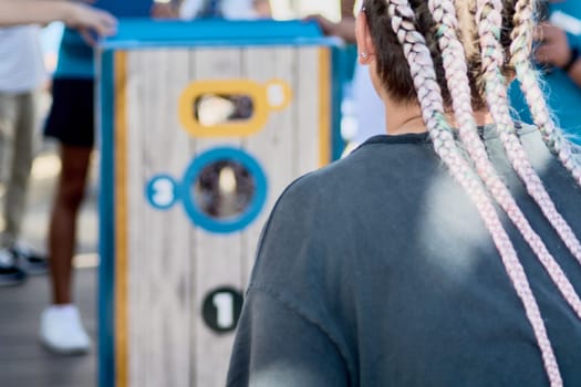 Vibrant cornhole game setup with a focused woman aiming her toss during a sunny outdoor recreational event.