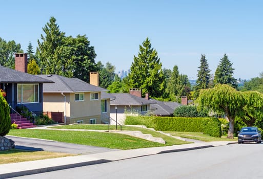 Street of residential houses with a car parked on side. Residential area with Metrotown view.