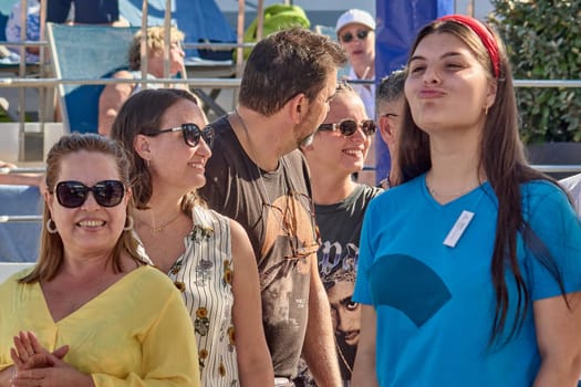 Catania. Italy - March 13, 2025: A group of people engaging with an energetic entertainer during an outdoor event, showcasing smiles and lively interaction in a sunny setting.