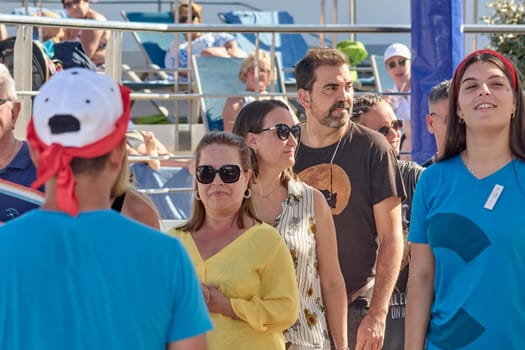Catania. Italy - March 13, 2025: Enthusiastic crowd surrounding a charismatic host who leads recreational activities, capturing fun and dynamic energy in a vibrant outdoor gathering.