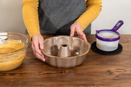Carefully greasing a bundt cake pan in preparation for baking a delicious gingerbread bundt cake with caramel frosting.