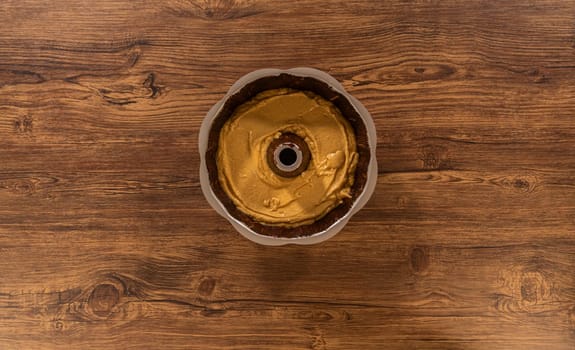 Flat lay. Pouring the gingerbread cake batter into the greased bundt cake pan, ready for a delightful caramel frosting.