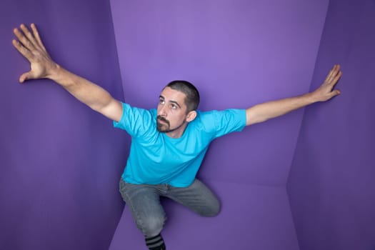 A man is sitting in a vibrant purple setting that evokes feelings of confinement and deep reflection on life