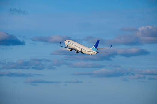 Lisbon, Portugal - Apr 29, 2024: ASL Airlines Boeing 737 shot mid-flight, ascending into clear blue sky with some clouds after takeoff on sunny day. Air traffic, vacations, travel, destinations, aircraft, international aviation, commercial airlines