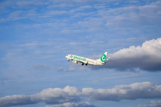 Lisbon, Portugal - Apr 29, 2024: Transavia Airlines Boeing 737 shot mid-flight, ascending into clear blue sky with some clouds after takeoff on sunny day. Air traffic, vacations, travel, destinations, aircraft, low-cost airline, commercial flight