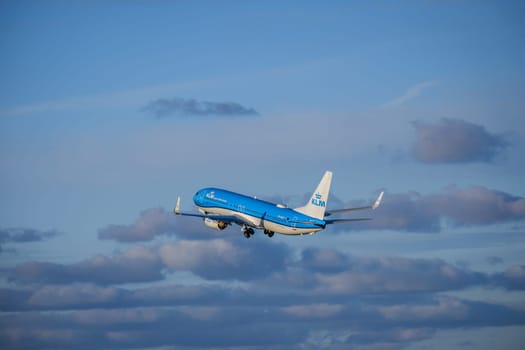 Lisbon, Portugal - Apr 29, 2024: KLM Royal Dutch Airlines aircraft Boeing 737-800 shot mid-flight, ascending into clear blue sky with some clouds, takeoff on sunny day. Vacations, travel, destinations, aircraft, low-cost airline, commercial flight