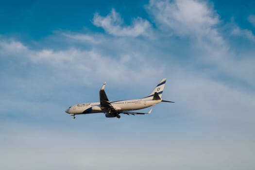 Lisbon, Portugal - Jan 14, 2025: El Al Airlines Boeing 737 shot mid-flight with landing gear extended, ready for landing on sunny day with clear blue sky and some soft clouds. Classic livery of Israel flag carrier.