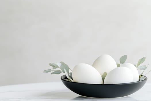 This minimalist Easter centerpiece showcases white Easter eggs elegantly placed in a black bowl, accompanied by fresh eucalyptus leaves. It creates a serene and stylish decoration for the holiday.