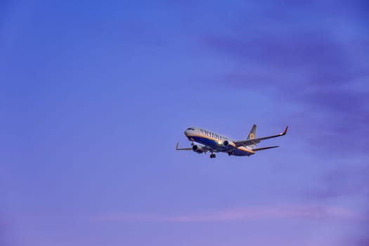 Lisbon, Portugal - Jan 14, 2025: Ryanair Boeing 737 aircraft shot mid-descent with landing gear extended, flying in sunset purple sky, some clouds. Airplane, low-cost airline, budget-friendly, European air travel, weekend getaway, summer vacations