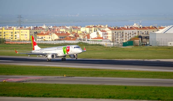 Lisbon, Portugal - Apr 3, 2024: TAP Air Portugal Embraer E190 aircraft approaching runway at Lisbon airport under clear blue skies, ready to land. Summer haze, vacations, travel destination, busy travel hub, Portuguese national aviation livery.