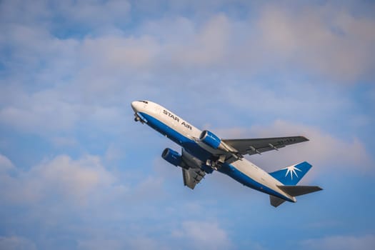 Lisbon, Portugal - Apr 29, 2024: Maersk Air Cargo Star Air Boeing 767 cargo plane take off in Humberto Delgado Airport in blue sky with white clouds on sunny day. Shot mid-flight, aircraft, air freight, international shipment, cargo operations