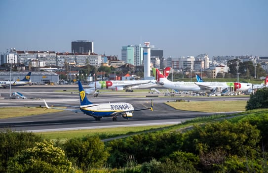 Lisbon, Portugal - Apr 3, 2024: Air Portugal or TAP, Ryanair and Azores airlines airplanes parked at Lisbon airport apron, Ryanair aircraft fast moving on runway. Clear blue sky, sunny day, vacation, travel destination, city landscape in background