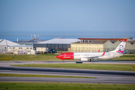Lisbon, Portugal - Apr 3, 2024: Norwegian airline Boeing 737-800 aircraft taxiing on runway at Lisbon airport, sunny day, clear sky and hangars in background. Vacations, weekend getaway, low-cost airline, summer travel destination, international hub