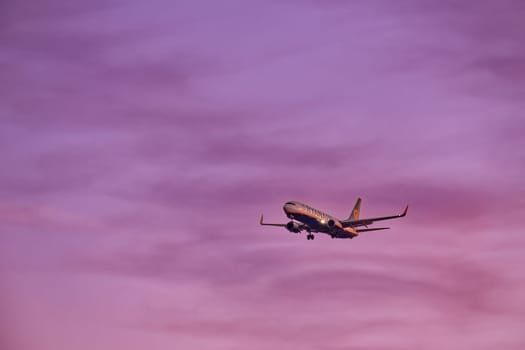 Lisbon, Portugal - Jan 14, 2025: Ryanair Boeing 737 aircraft shot mid-descent with landing gear extended, flying in sunset purple sky, some clouds. Airplane, low-cost airline, budget-friendly, European air travel, weekend getaway, summer vacations