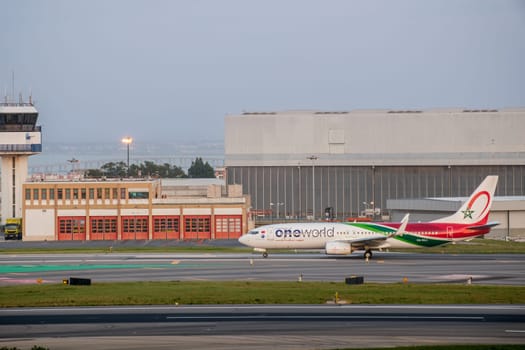 Lisbon, Portugal - Apr 3, 2024: Royal Air Maroc Boeing 737-800 airline aircraft taxiing on runway at Lisbon airport, clear sky, ATC control tower and hangars in background. Vacations,, summer travel destination, international hub, OneWorld group