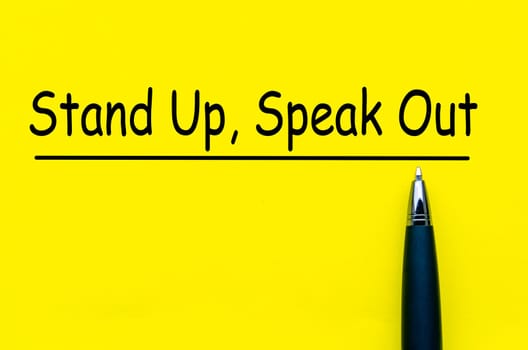 Stand Up and Speak Out Courage text on yellow notepad. Speak up culture.