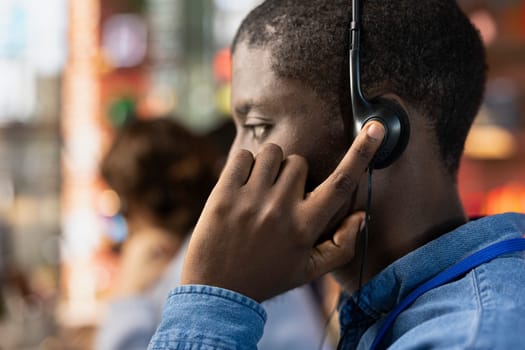 Call center agent dealing with unsatisfied customers, speaking with them using headset in office, close up. African american customer support representative handling clients complaints in workspace