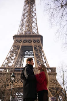 A young couple shares a loving gaze near the Eiffel Tower in Paris. Their affectionate connection captures the essence of romance.