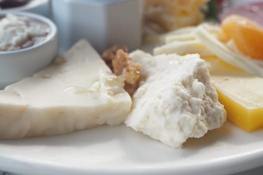 A selection of different cheeses on a platter alongside nuts and spreads