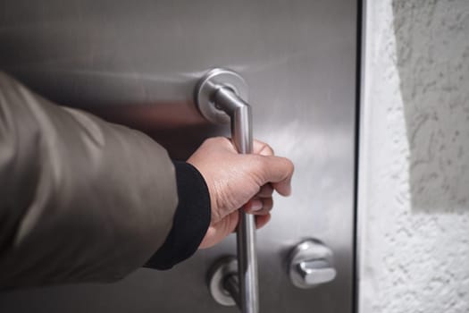 A person reaches for a sleek metallic door handle with intent.