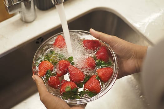 Cleaning Fresh strawberries at kitchen sink ,