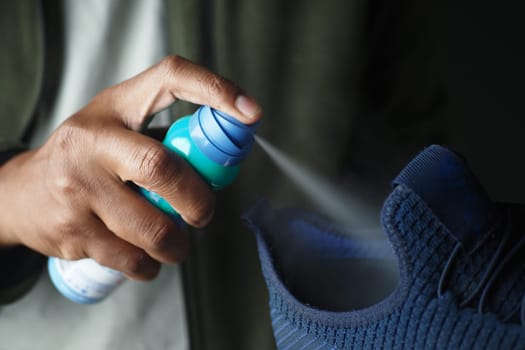 A person cleans a sneaker using a spray can at home.