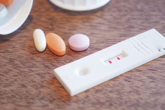 pregnancy Test kit with pills on wooden table in a medical setting,
