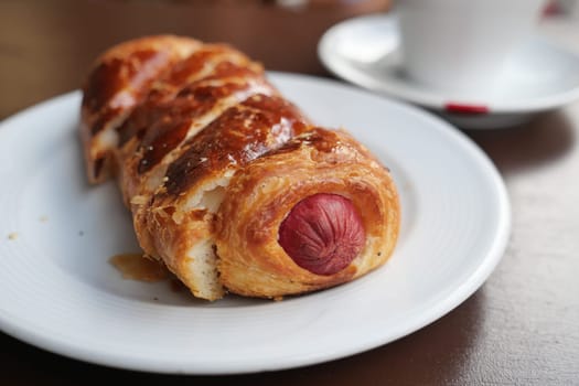 Freshly baked pastry with a savory sausage inside on a plate.