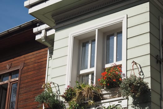 Bright flowers adorn window boxes of a charming green house.