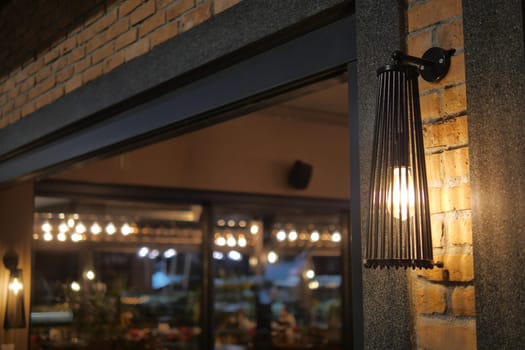 Warm light from a stylish lamp sets the mood at a restaurant entrance.