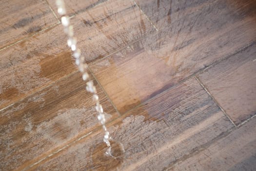 Water is cascading down onto a wooden floor, creating ripples.
