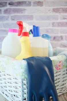 Various cleaning supplies are neatly arranged in a basket with gloves nearby.