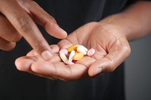 A person is displaying various colorful pills in their palm.