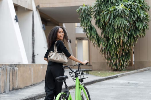 Turning back with a smile, the woman showcases her environmentally friendly commute, epitomizing the blend of health and style in a city setting.
