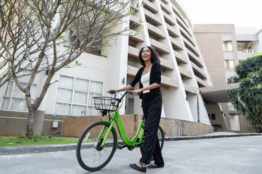 With a broad smile, the woman enjoys her ride on a sunny day, showcasing how biking can enhance urban living and promote a sustainable lifestyle.