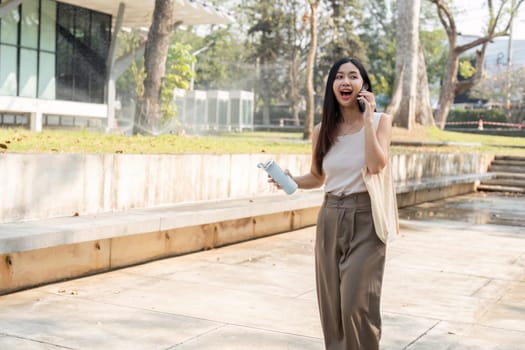 A young woman walks with excitement while talking on her phone, showcasing her commitment to a sustainable lifestyle.