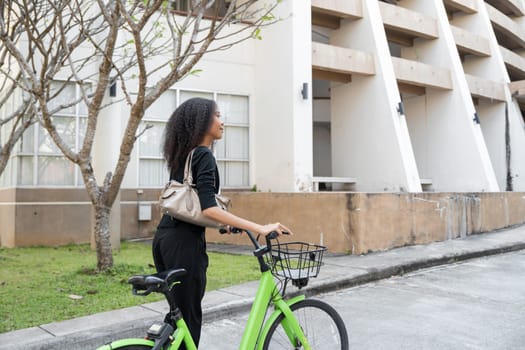 The woman stands confidently next to her bike, embodying a modern approach to eco-friendly travel while engaging with her urban environment.